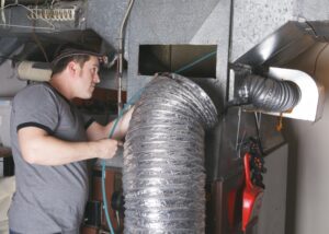 Technician working on HVAC unit ventilation shaft.